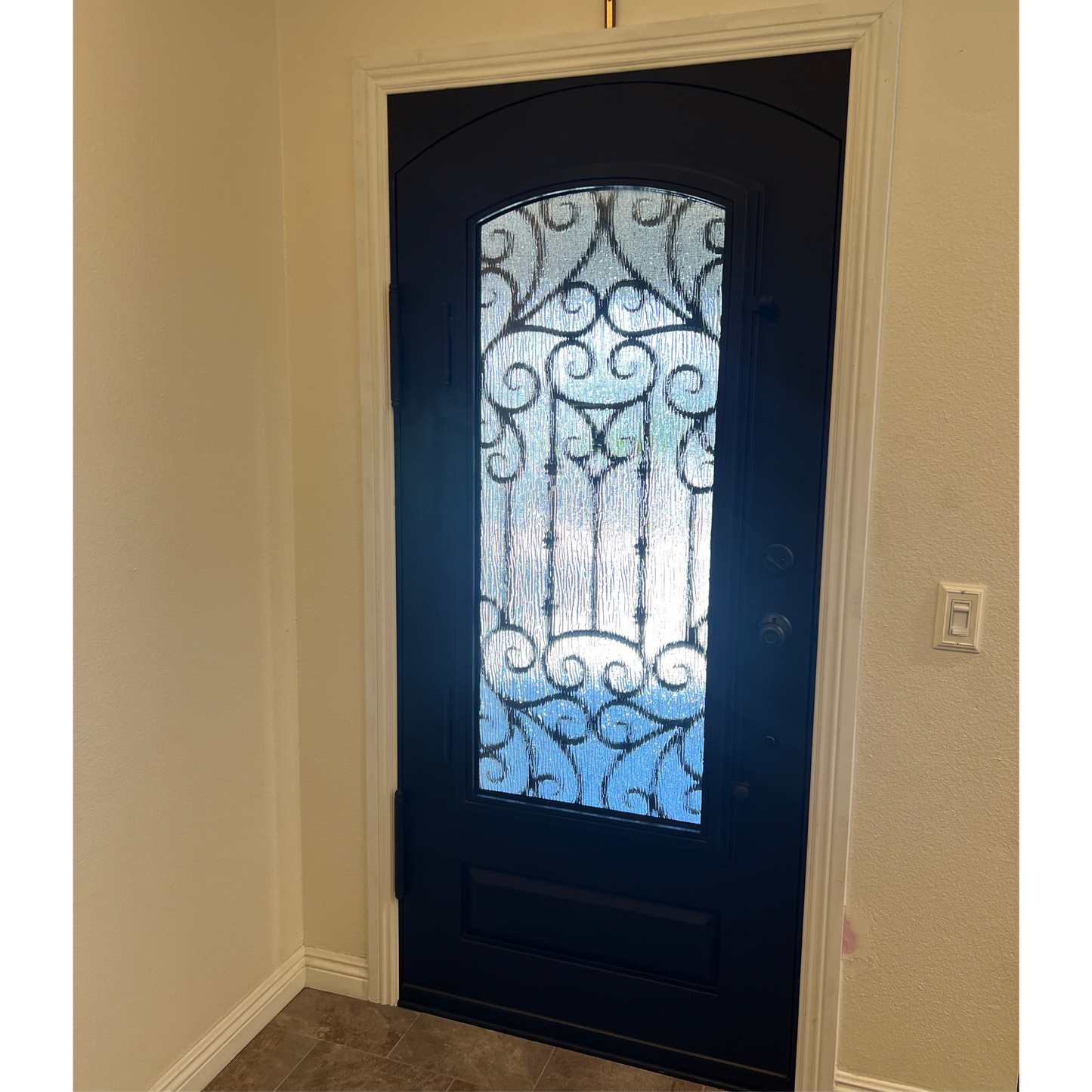 Decorative black door with glass panel in a room with beige walls.
