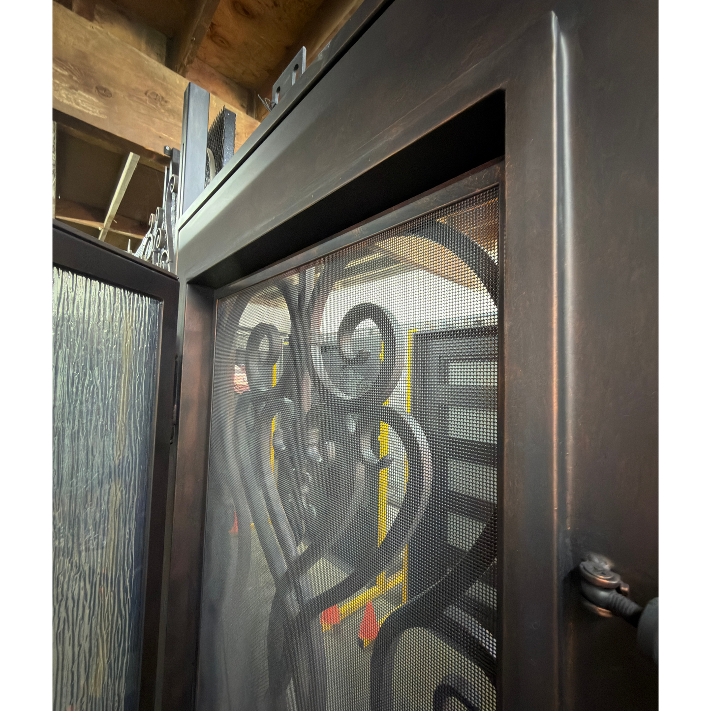 Decorative metal screen door with intricate designs on a wooden background