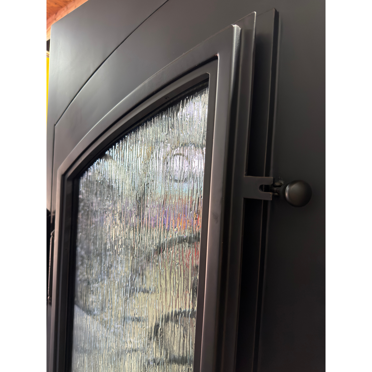 Close-up of a black metal door with a textured glass panel