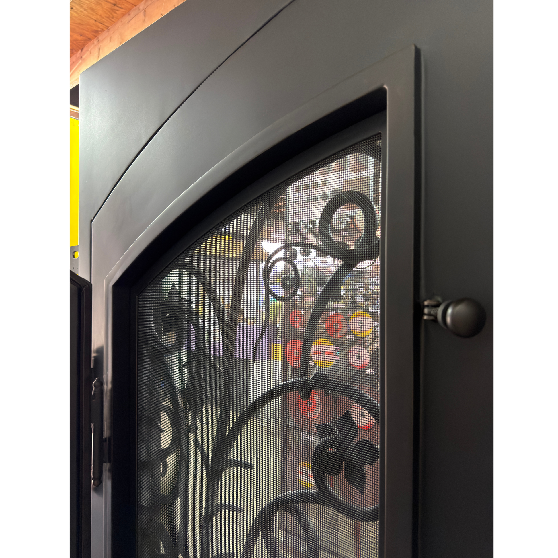 Decorative fireplace screen with intricate black metal design on a white background