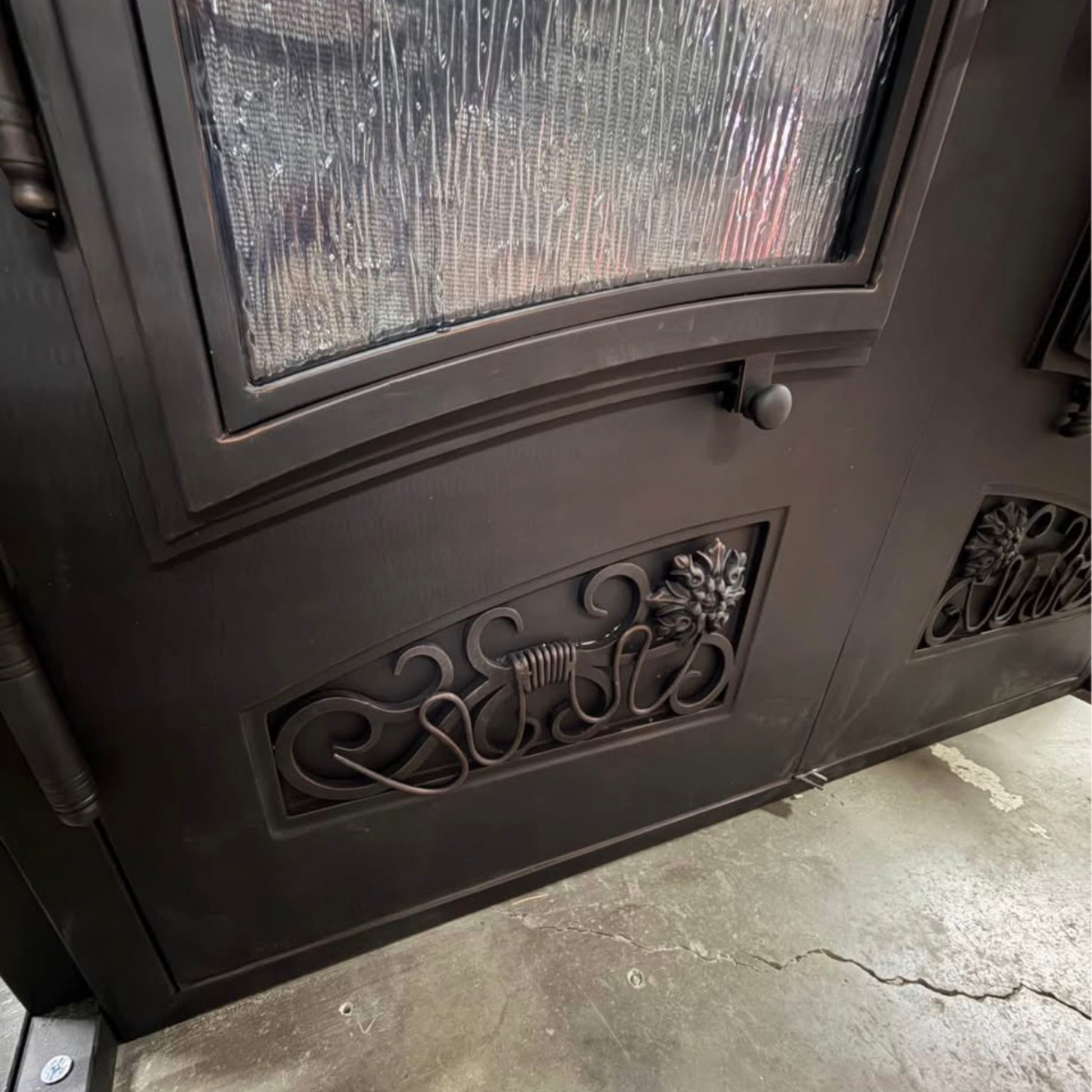 Decorative metal door with intricate designs on a concrete floor