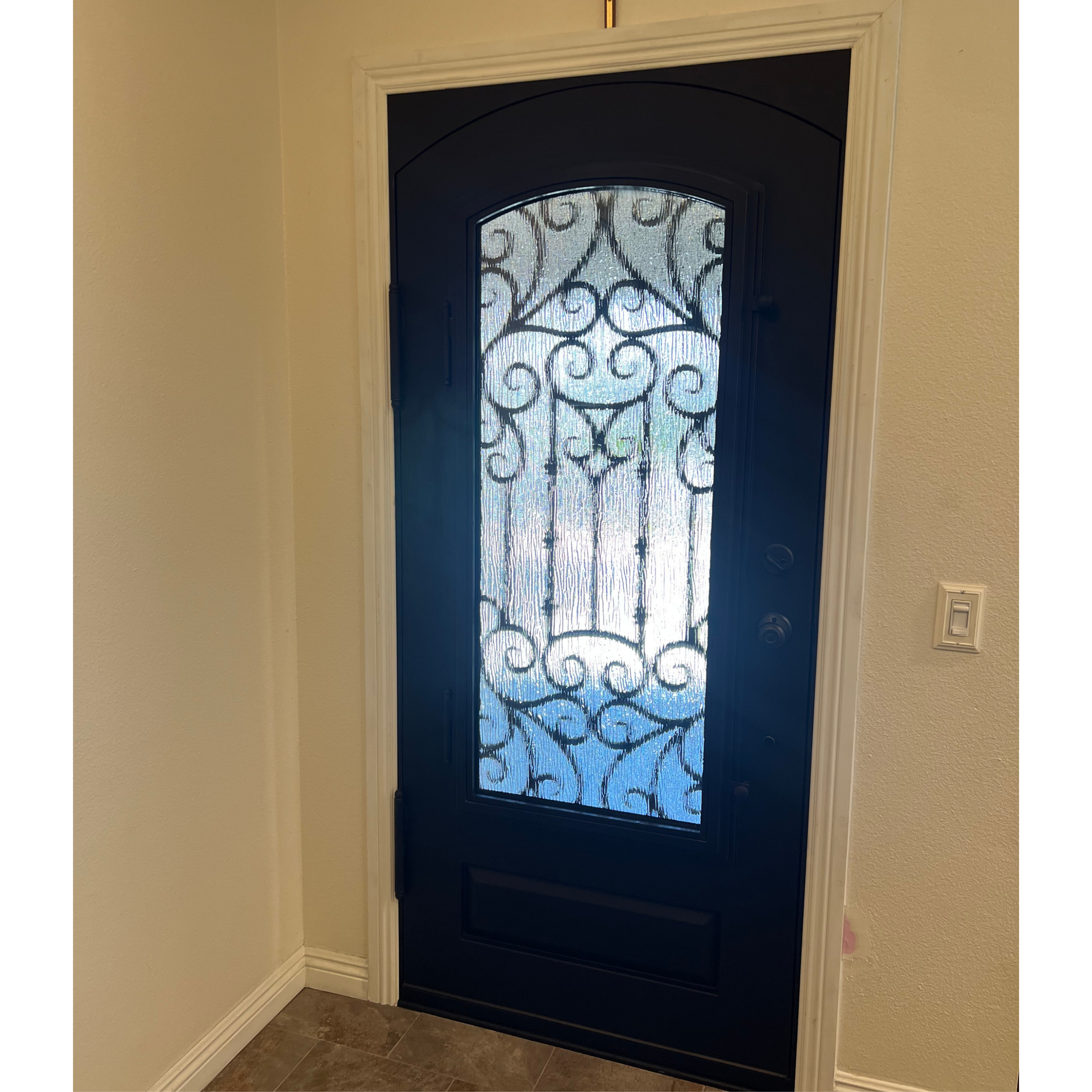 Decorative black door with glass panel in a room with beige walls.