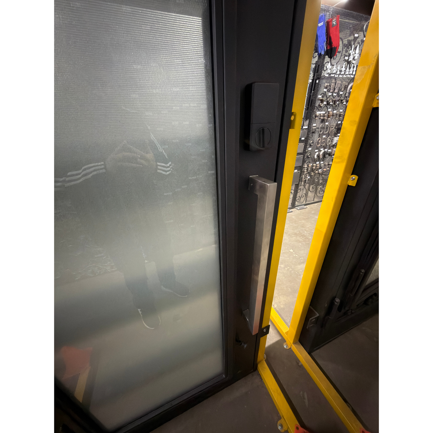 Close-up of a screen door with a yellow frame and black hardware.