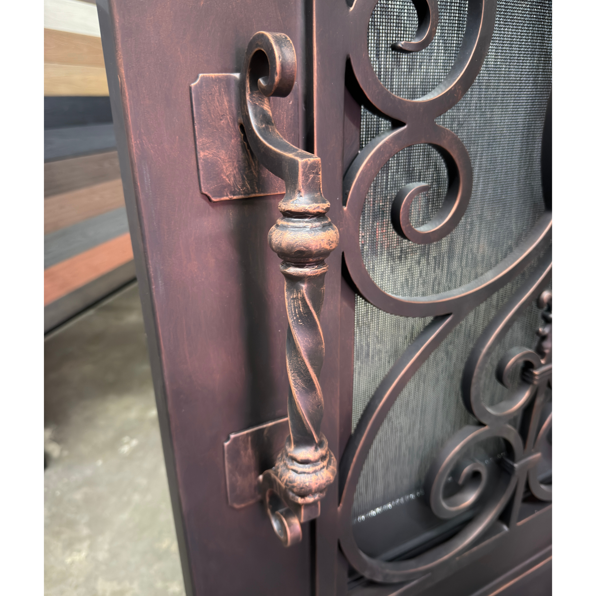 Close-up of a decorative metal door with intricate designs and a handle.