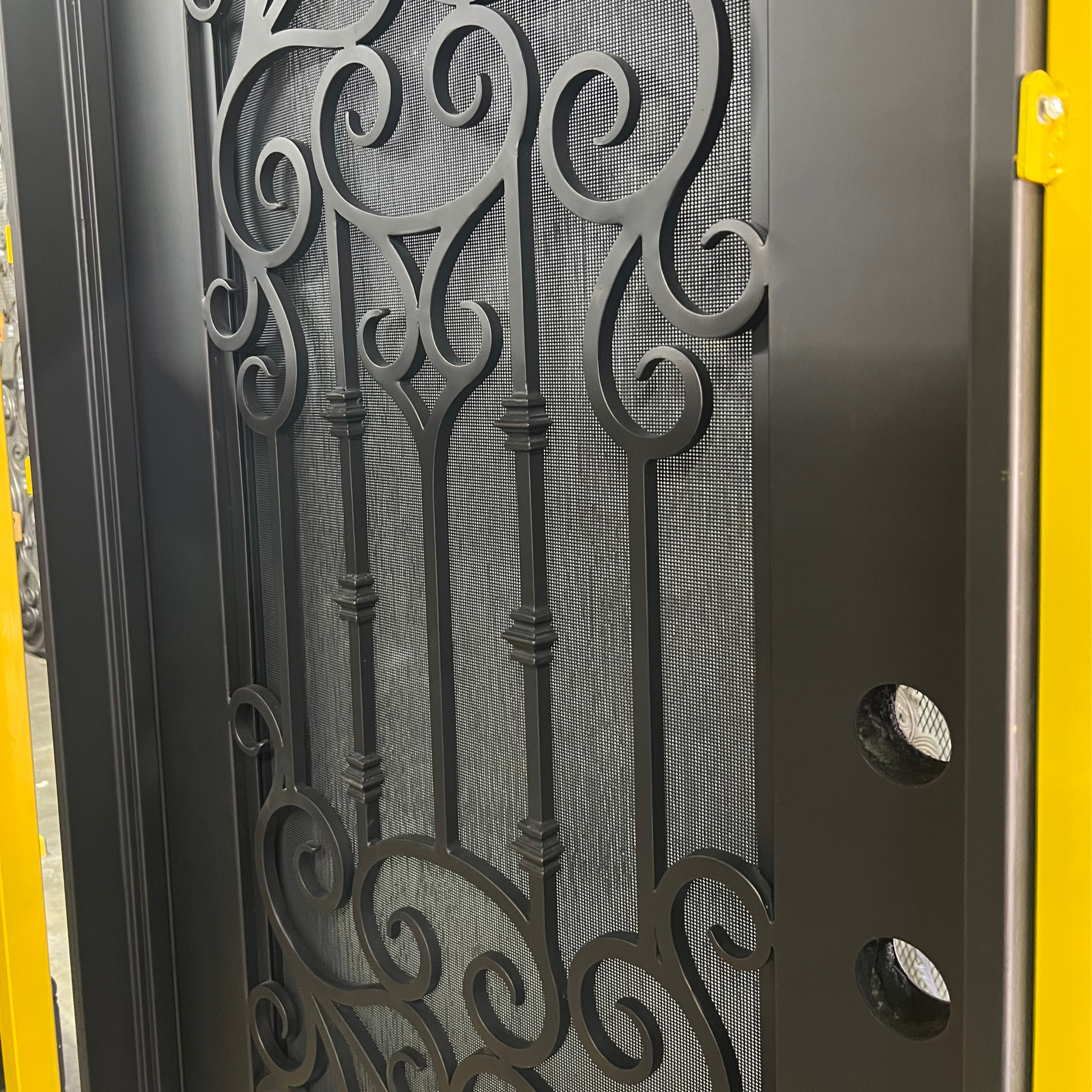 Decorative metal gate with intricate designs on a yellow background
