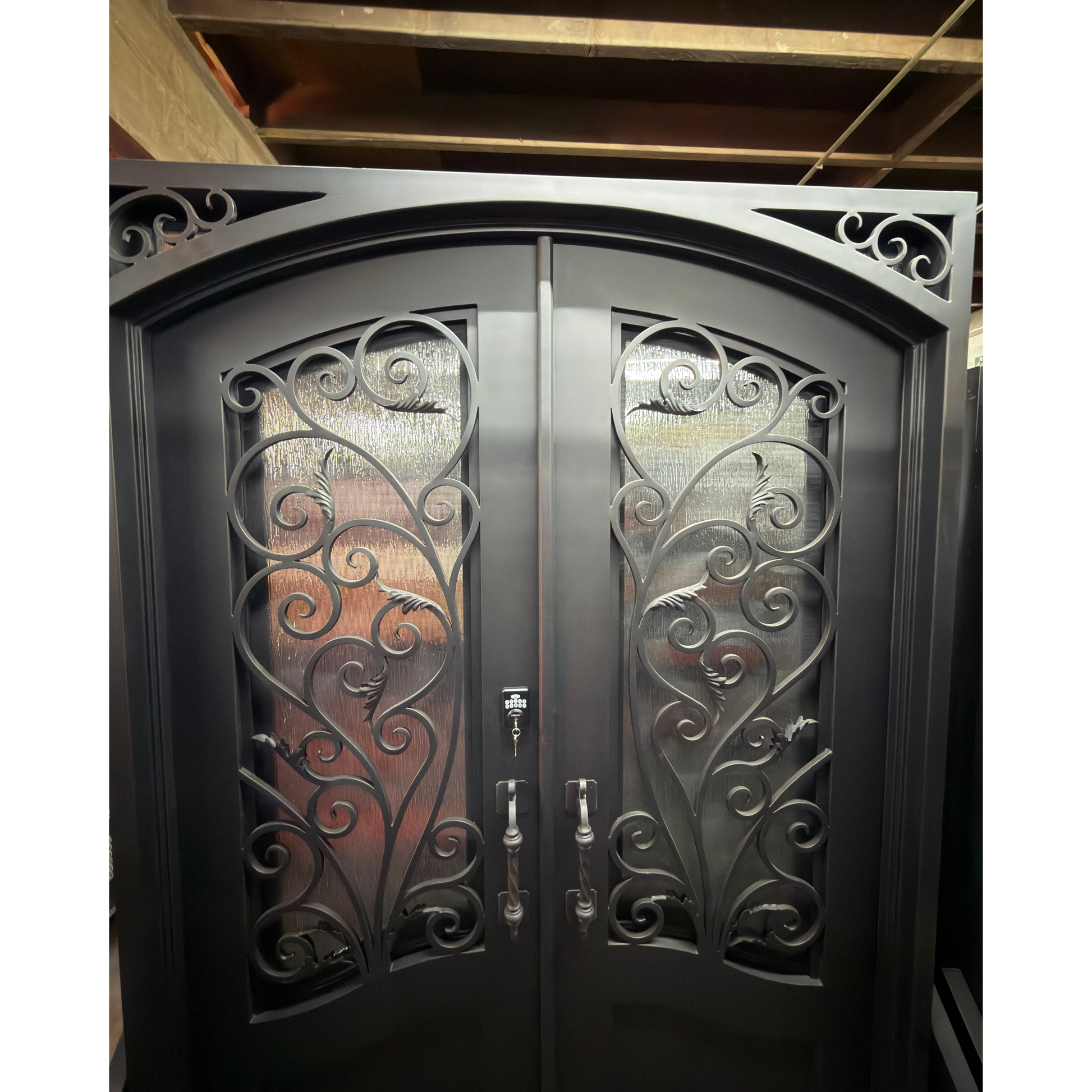 Decorative wrought iron double doors with intricate designs in a warehouse setting.