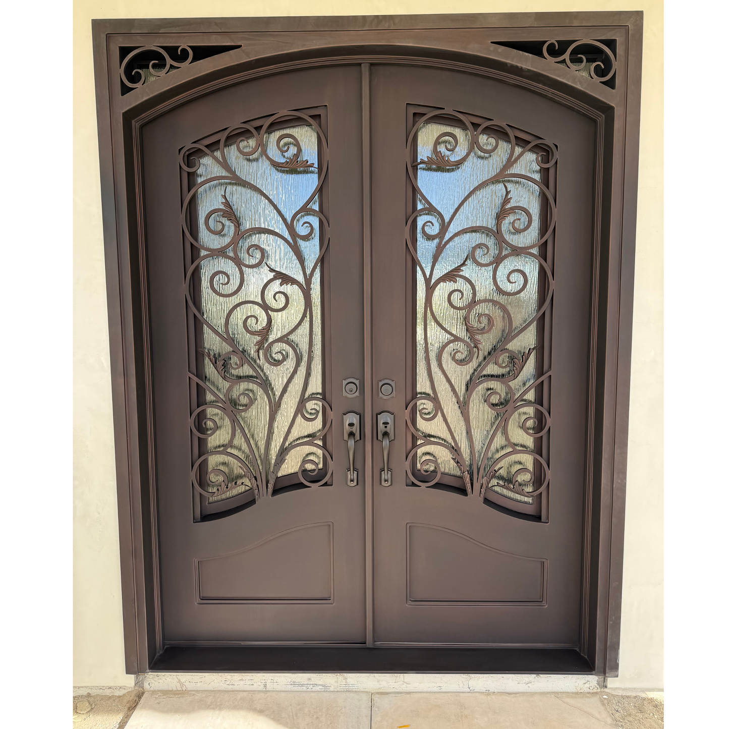 Decorative iron double door with intricate designs on a beige wall.